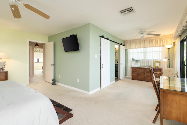 bedroom featuring ceiling fan, light colored carpet, and a barn door