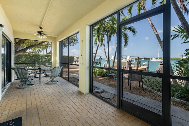 sunroom featuring a water view and ceiling fan