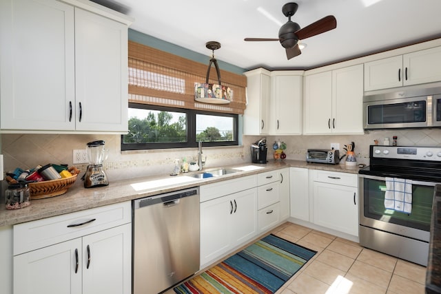 kitchen featuring stainless steel appliances, white cabinetry, sink, and decorative light fixtures