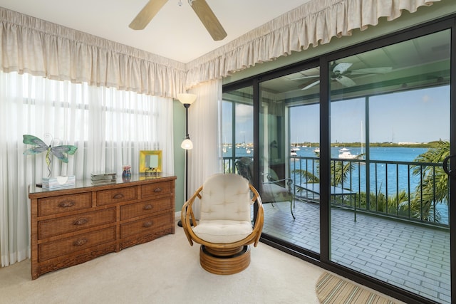 living area with a water view, carpet, and ceiling fan