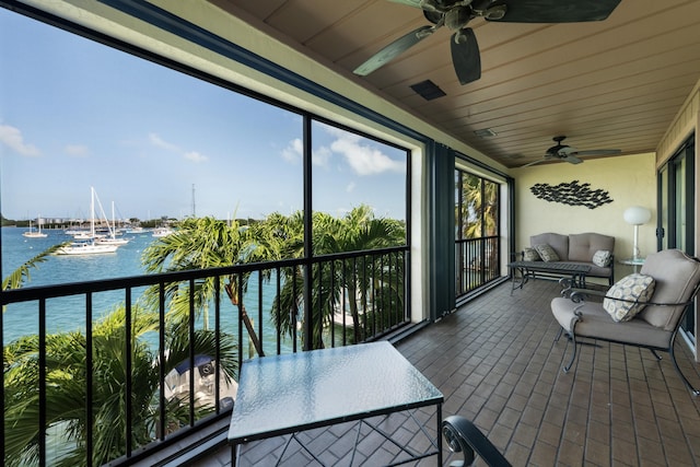 sunroom featuring a water view and ceiling fan