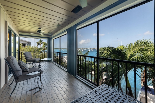 sunroom / solarium featuring a water view and ceiling fan