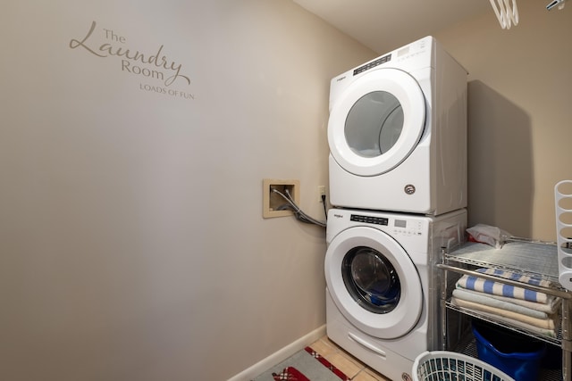 laundry area featuring stacked washer / drying machine and light tile patterned floors