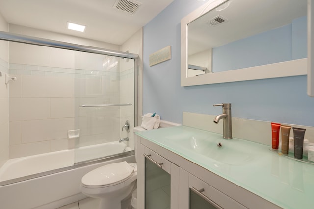 full bathroom with vanity, bath / shower combo with glass door, and toilet