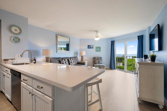 kitchen with dishwasher, sink, a breakfast bar area, white cabinets, and a center island with sink