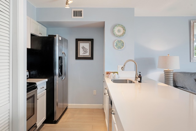 kitchen with stainless steel appliances, light hardwood / wood-style floors, sink, and white cabinets