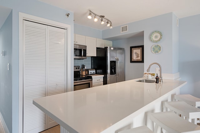 kitchen featuring appliances with stainless steel finishes, kitchen peninsula, sink, and a breakfast bar area