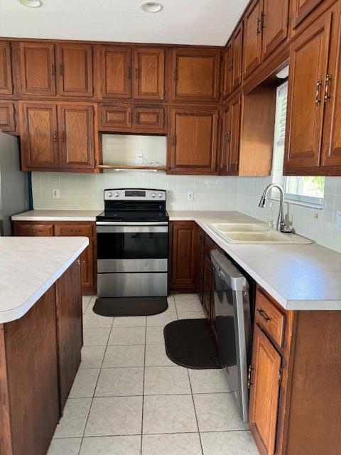 kitchen with sink, decorative backsplash, stainless steel appliances, and light tile patterned flooring