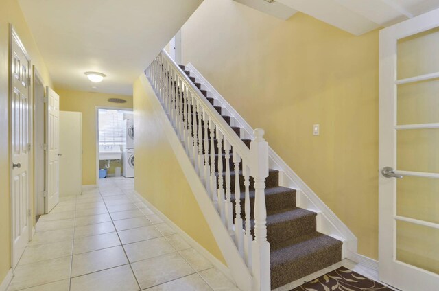 stairway with tile patterned flooring, sink, and washer / dryer