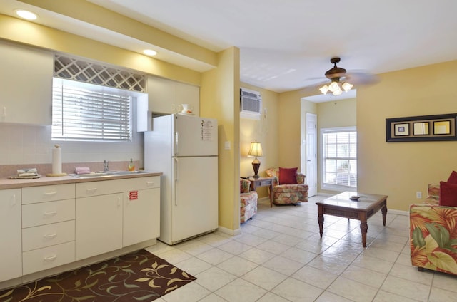 kitchen with light tile patterned flooring, sink, decorative backsplash, white refrigerator, and a wall unit AC