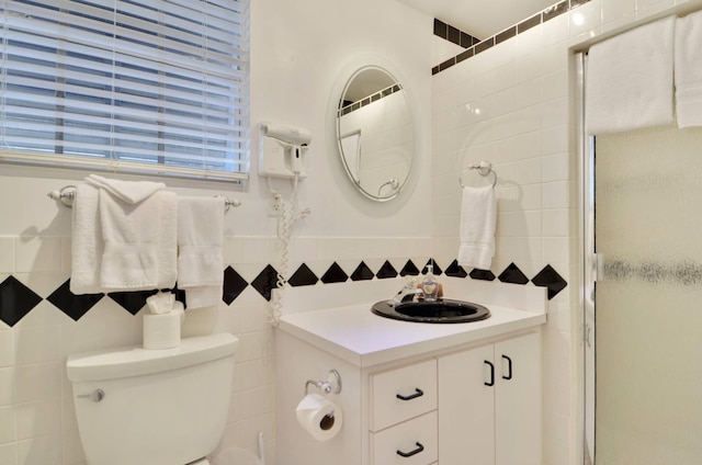 bathroom featuring vanity, a shower with door, tile walls, and toilet