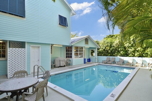 view of swimming pool featuring a grill and a patio