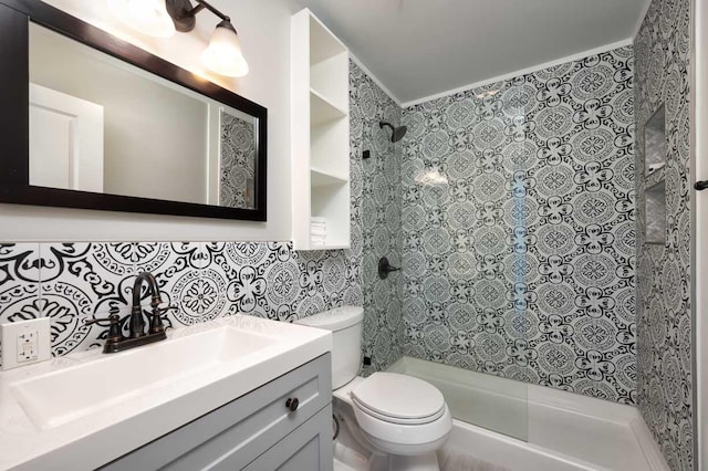 bathroom featuring toilet, tile walls, a tile shower, vanity, and backsplash