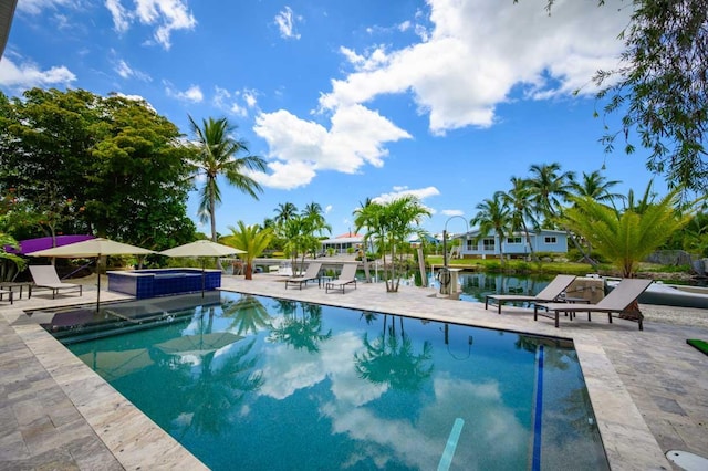 view of pool featuring a patio area, an in ground hot tub, and a water view