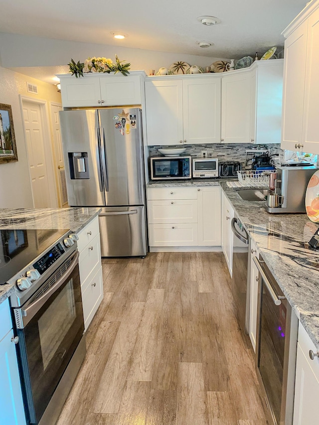 kitchen featuring white cabinetry, stainless steel appliances, light stone counters, wine cooler, and light wood-type flooring