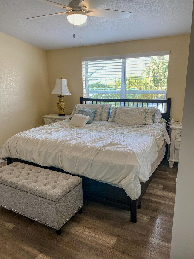 bedroom with ceiling fan, dark hardwood / wood-style floors, and a textured ceiling