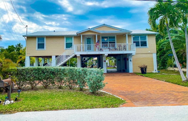 beach home featuring a carport, a front yard, and covered porch