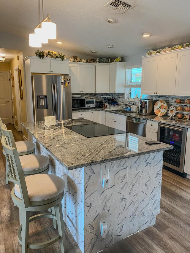 kitchen with wine cooler, pendant lighting, a kitchen island, and appliances with stainless steel finishes