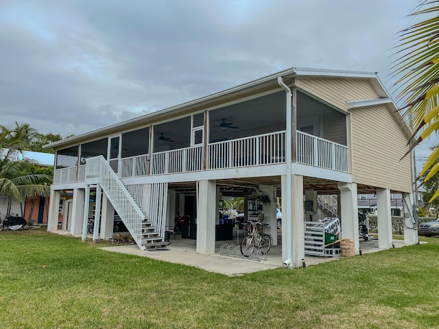 back of property with ceiling fan, a sunroom, a patio area, and a lawn