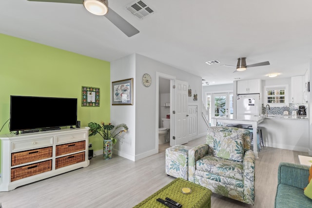 living room featuring light wood-type flooring, sink, and ceiling fan