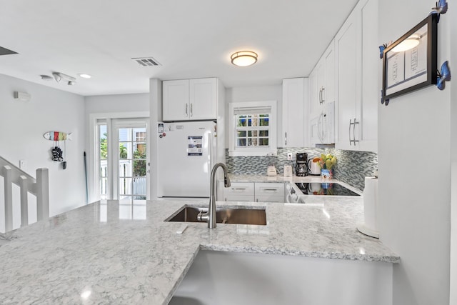 kitchen with sink, white appliances, light stone counters, white cabinets, and decorative backsplash