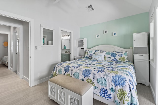 bedroom featuring ensuite bathroom, lofted ceiling, and light hardwood / wood-style flooring