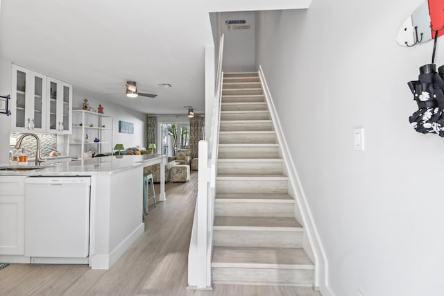 stairway with hardwood / wood-style flooring, ceiling fan, and sink