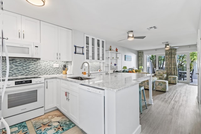 kitchen with white cabinetry, sink, white appliances, and kitchen peninsula