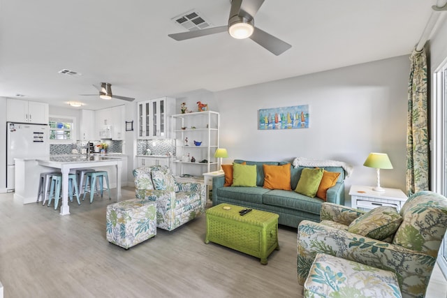 living room with light hardwood / wood-style flooring and ceiling fan