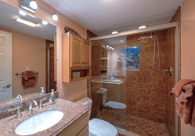 bathroom with walk in shower, vanity, and toilet