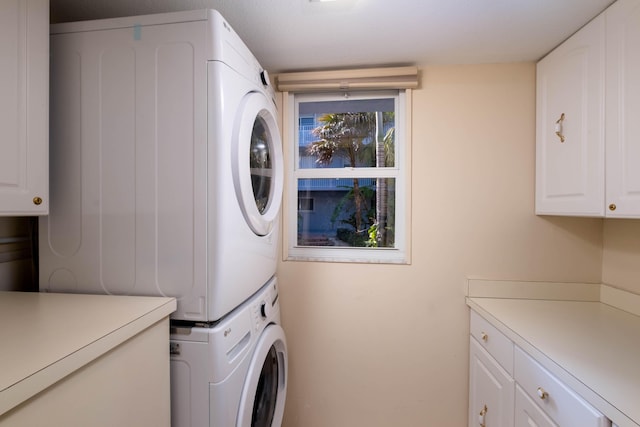 laundry room with cabinets and stacked washer / dryer