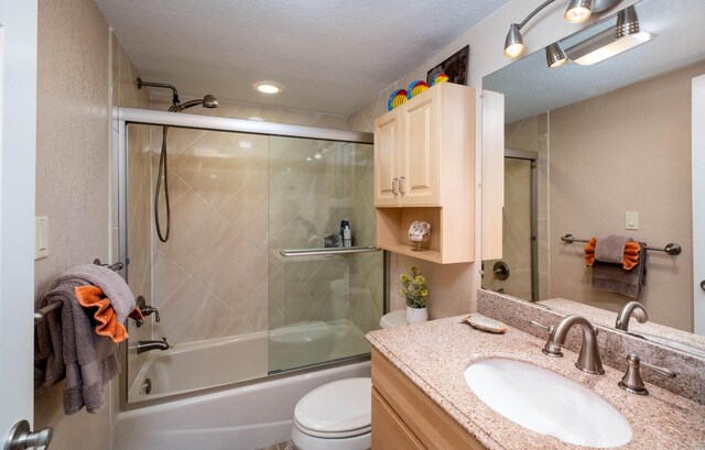 full bathroom with shower / bath combination with glass door, vanity, toilet, and a textured ceiling