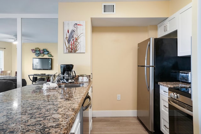 kitchen featuring stone countertops, white cabinetry, sink, light hardwood / wood-style floors, and stainless steel appliances