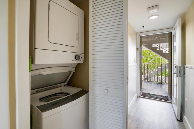 laundry area with light wood-type flooring and stacked washing maching and dryer