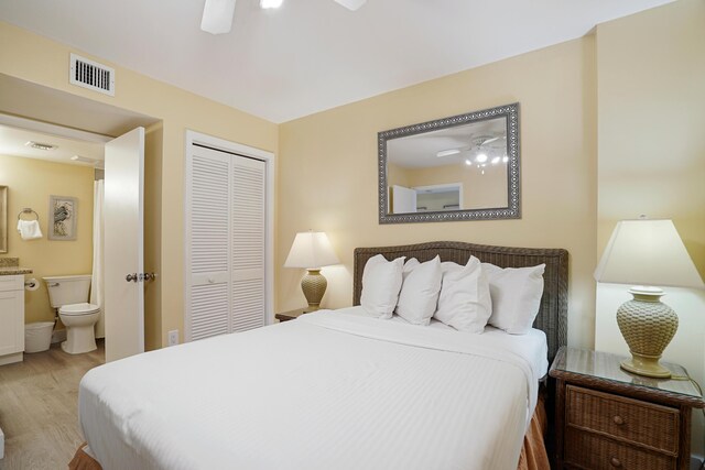 bedroom with ceiling fan, connected bathroom, light wood-type flooring, and a closet