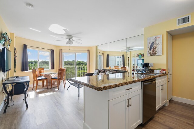 kitchen with white cabinetry, dishwasher, sink, dark stone countertops, and kitchen peninsula