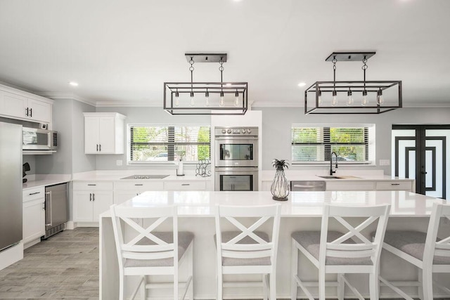 kitchen featuring appliances with stainless steel finishes, sink, white cabinets, a center island, and crown molding