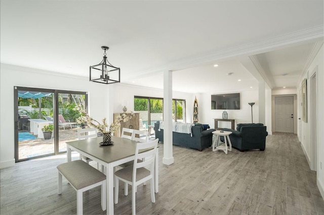 dining room with an inviting chandelier, ornamental molding, and light hardwood / wood-style floors