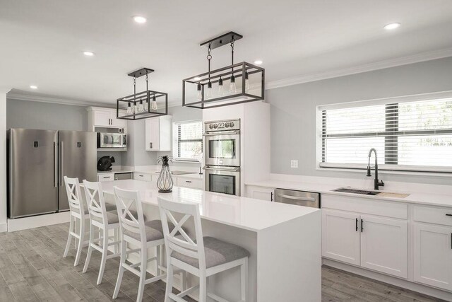 kitchen with sink, decorative light fixtures, a center island, appliances with stainless steel finishes, and white cabinets