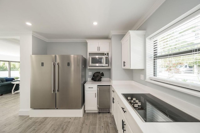 kitchen with crown molding, stainless steel appliances, light hardwood / wood-style floors, and white cabinets