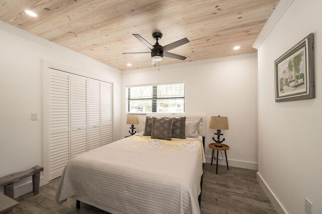 bedroom with dark wood-type flooring, ornamental molding, a closet, and wooden ceiling