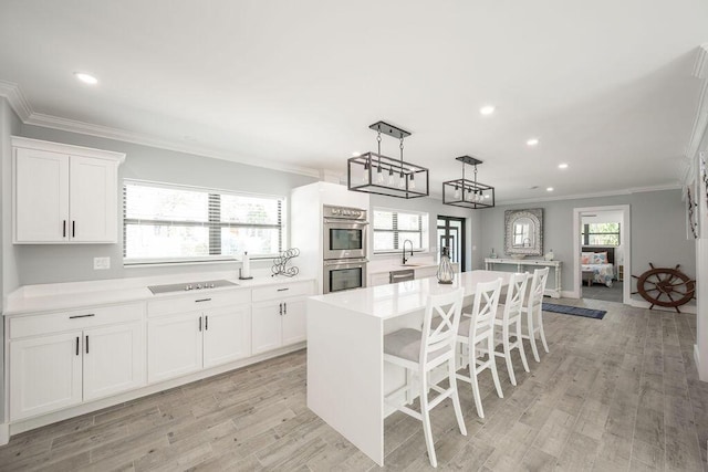 kitchen featuring crown molding, a breakfast bar area, stainless steel appliances, a center island, and white cabinets