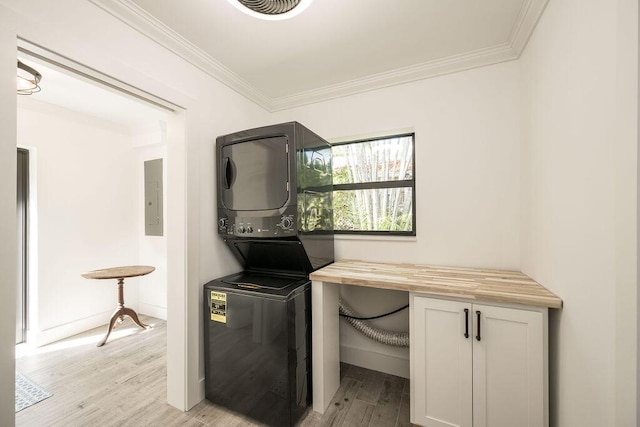 clothes washing area with stacked washer / drying machine, crown molding, electric panel, and light hardwood / wood-style floors