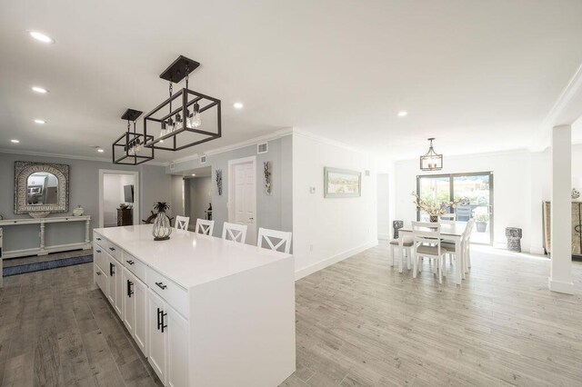 kitchen featuring white cabinetry, hanging light fixtures, a center island, and light wood-type flooring