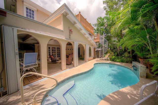 outdoor pool with a patio and stairs