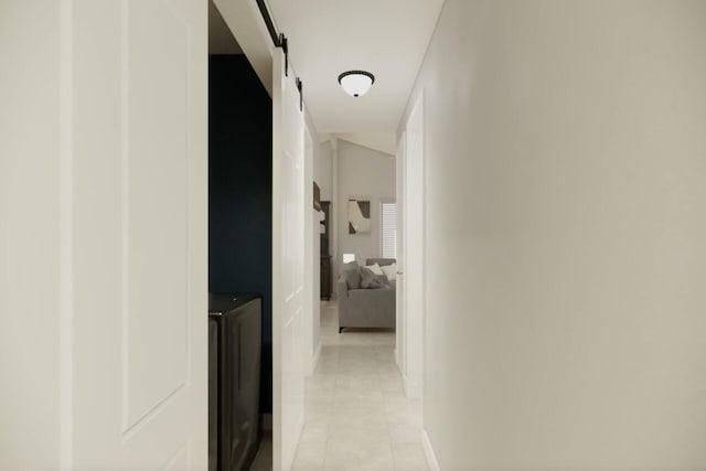 hallway with washer / dryer, light tile patterned floors, a barn door, and baseboards