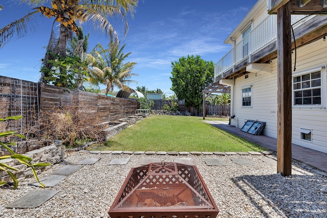 view of yard with a fenced backyard, an outdoor fire pit, and a balcony