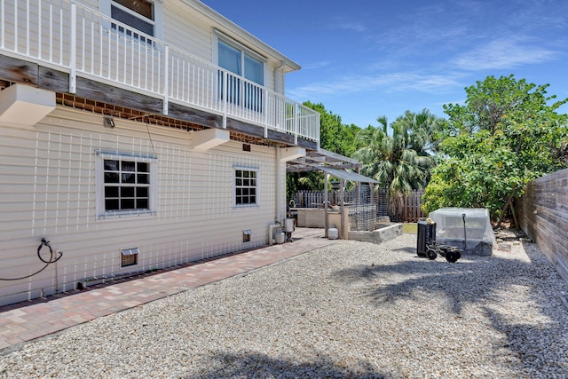 rear view of property with a balcony, a patio, fence, and crawl space