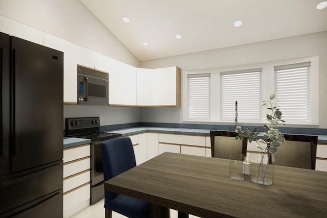 kitchen featuring freestanding refrigerator, dark countertops, white cabinets, stove, and vaulted ceiling