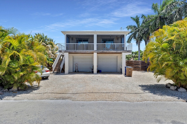 coastal inspired home with stairs, driveway, a garage, and fence